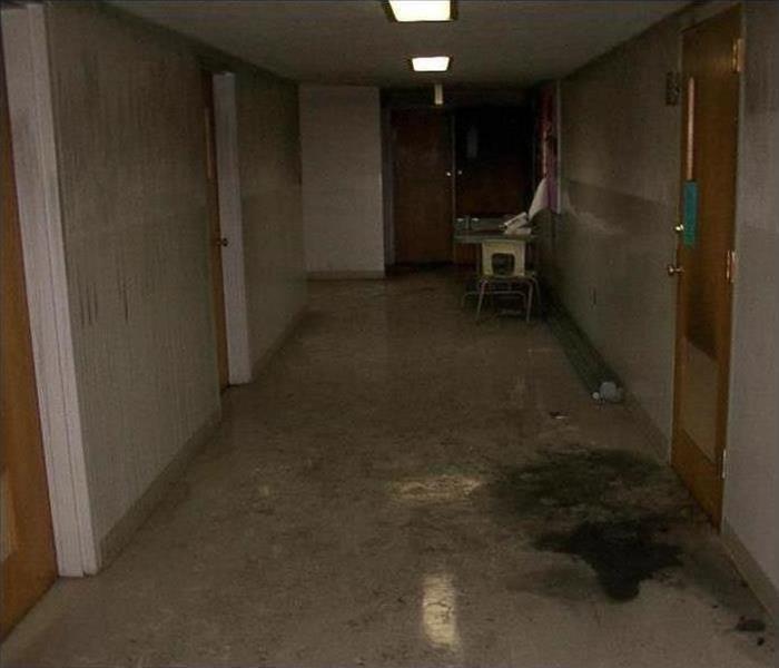 Commercial hallway filled with water and dirt