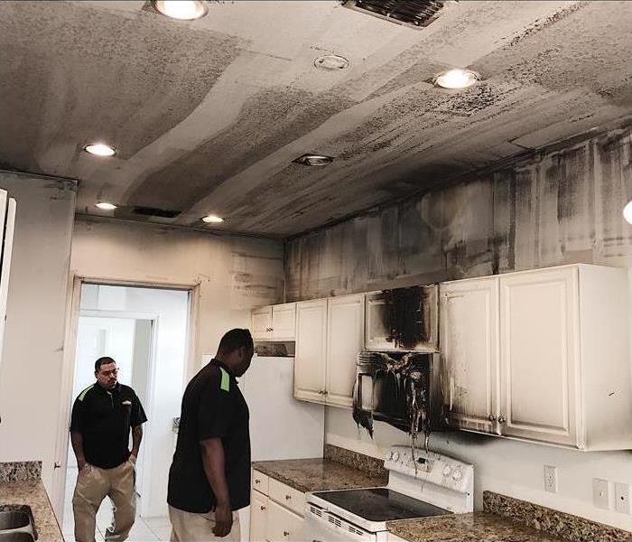 Two men in a kitchen with burned cabinets