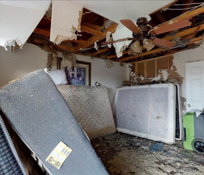 Collapsed ceiling of a room with hanging drywall and a dehumidifier in the room