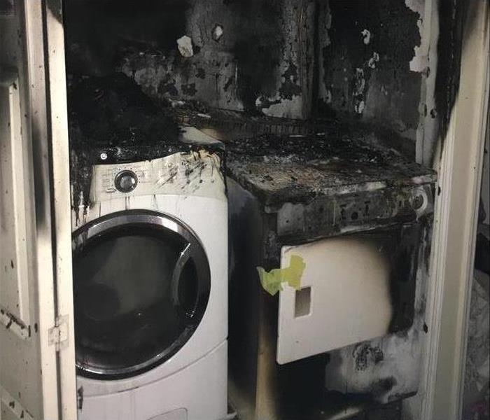 Washing machine and dryer in a closet, burnt and covered in soot